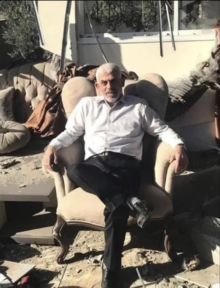 Yahya Sinwar sitting on a couch, in the sun amidst rubble, smiling